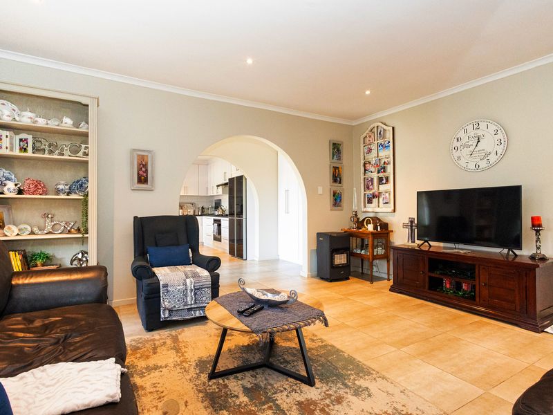 Open plan living area featuring tiled flooring, recessed lighting, and a distinctive arched entryway leading to the kitchen.