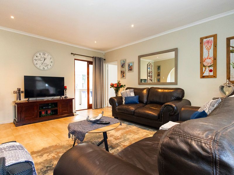 A comfortable living room featuring tiled flooring, recessed downlighting, and a sliding glass door providing access to the outdoor area.