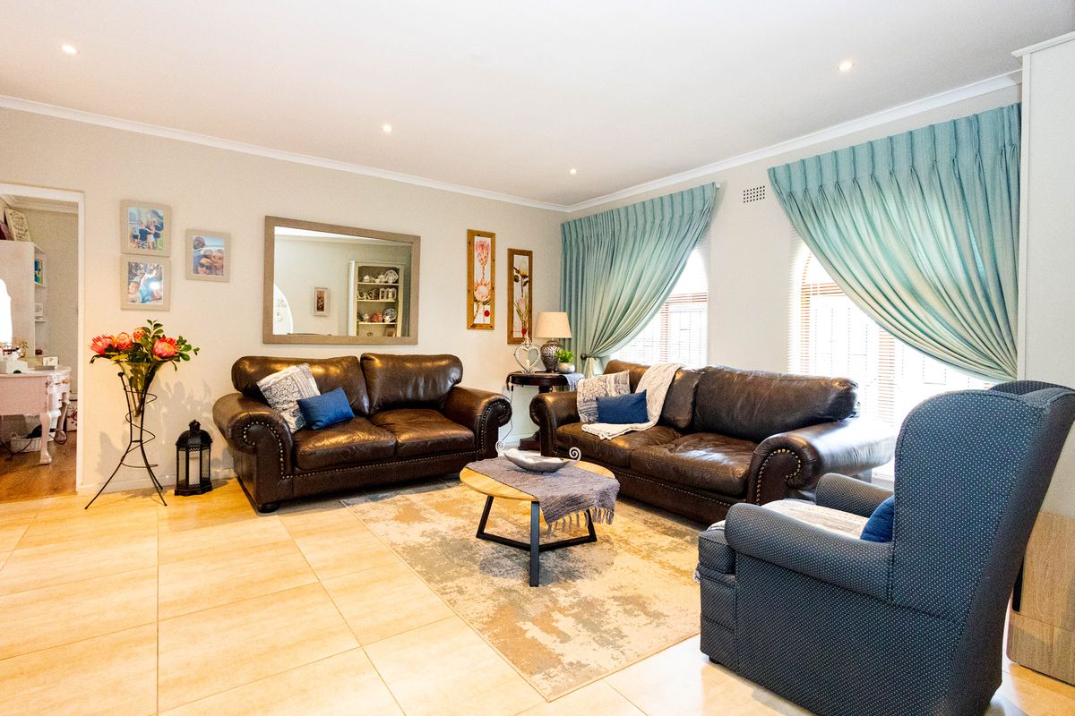 A well-maintained living room featuring neutral tiled flooring, recessed downlighting, and classic coving, creating a comfortable and inviting space.