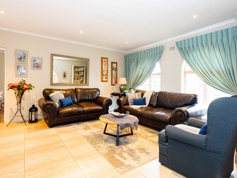 A well-maintained living room featuring neutral tiled flooring, recessed downlighting, and classic coving, creating a comfortable and inviting space.