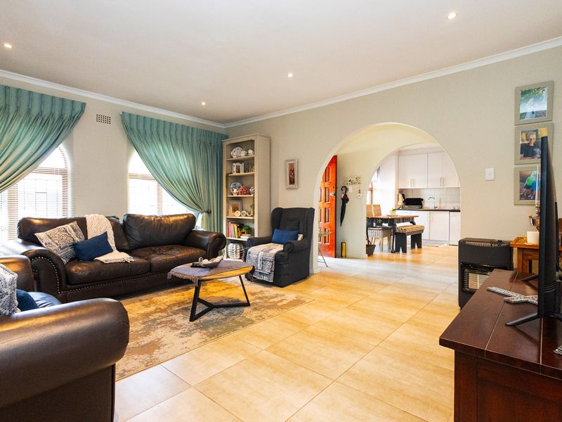 Spacious open-plan living area featuring tiled flooring, recessed lighting, and a distinctive archway leading to the kitchen and dining space.