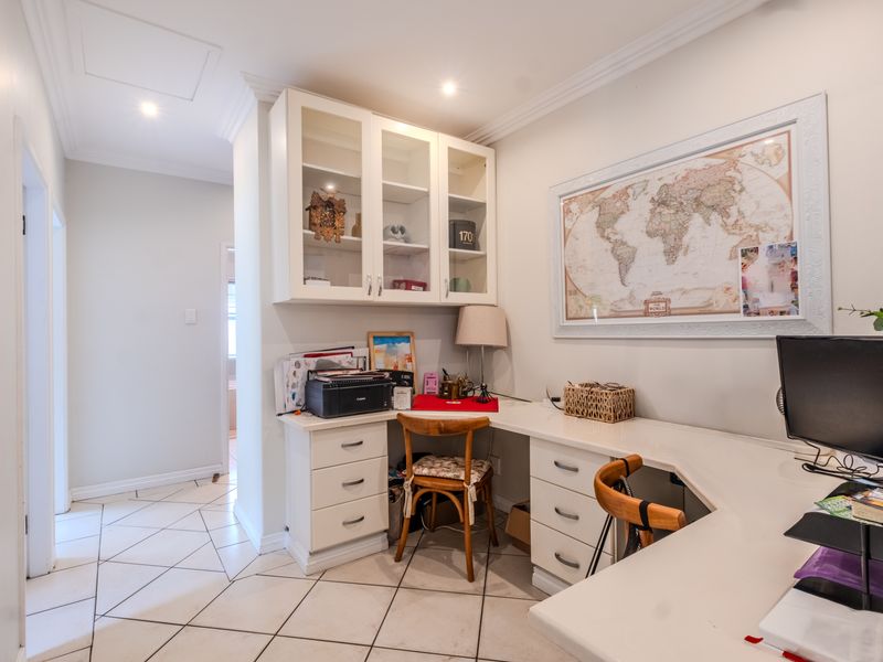 A functional home office space featuring built-in desk cabinetry, tiled flooring, and recessed lighting, providing a dedicated workspace within the townhouse.