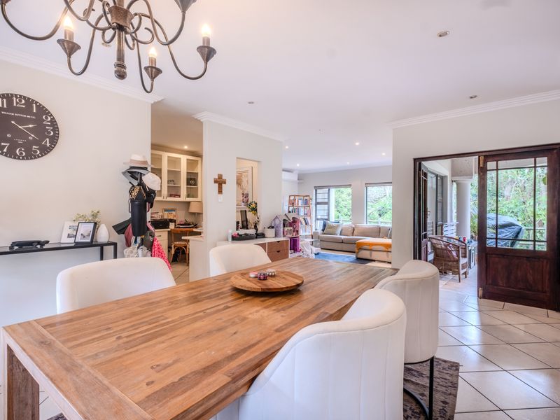 Spacious open-plan dining and living area featuring tiled floors, recessed lighting, and direct access to an outdoor patio through a timber-framed glass door.