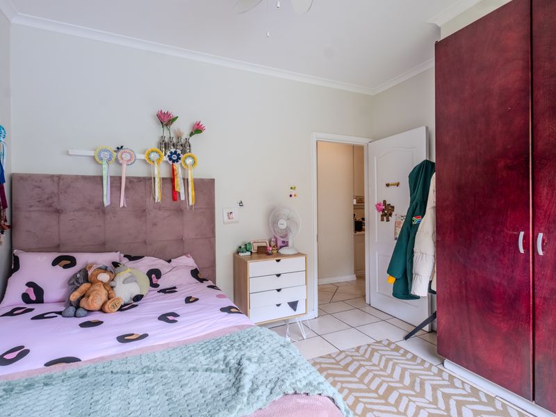 A bedroom featuring tiled flooring, a built-in wardrobe, and a ceiling fan, providing a functional and well-maintained living space.