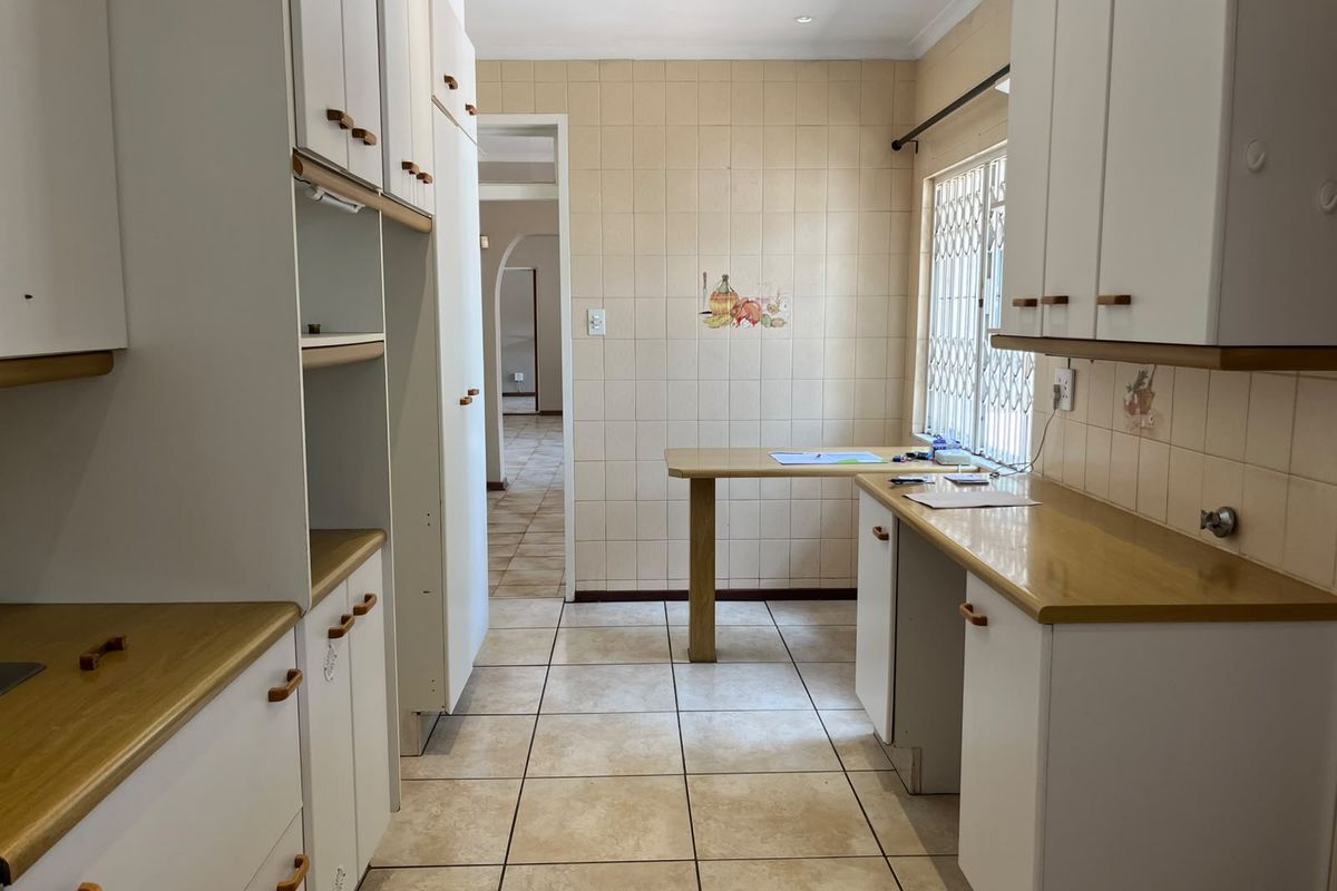 A functional kitchen featuring white built-in cabinetry, laminate countertops, and neutral ceramic tiling throughout, offering a clean and practical workspace.