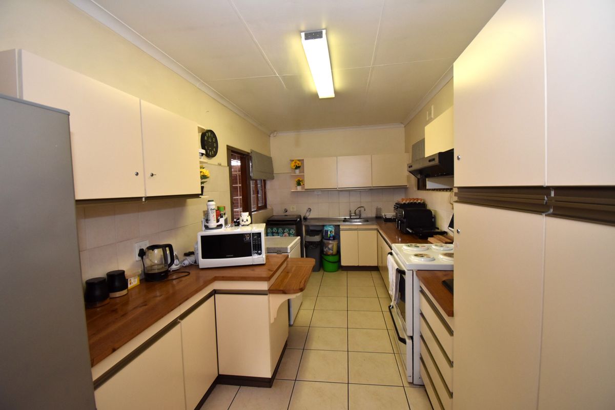 A functional galley-style kitchen featuring built-in cabinetry, laminate countertops, and tiled flooring, offering a practical layout with potential for modern updates.