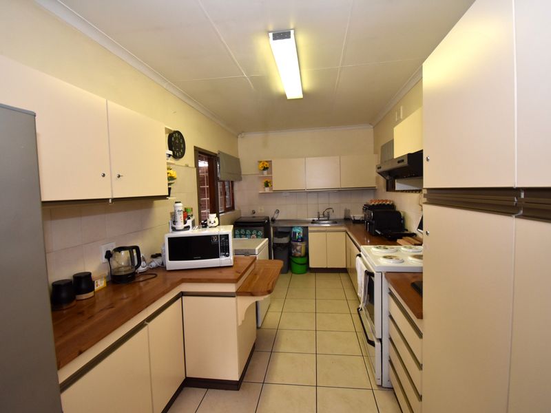 A functional galley-style kitchen featuring built-in cabinetry, laminate countertops, and tiled flooring, offering a practical layout with potential for modern updates.