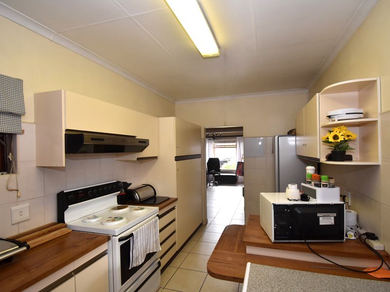 Functional kitchen featuring built-in cabinetry, tiled splashbacks, and tiled flooring, offering a practical layout with direct access to the adjacent living area.
