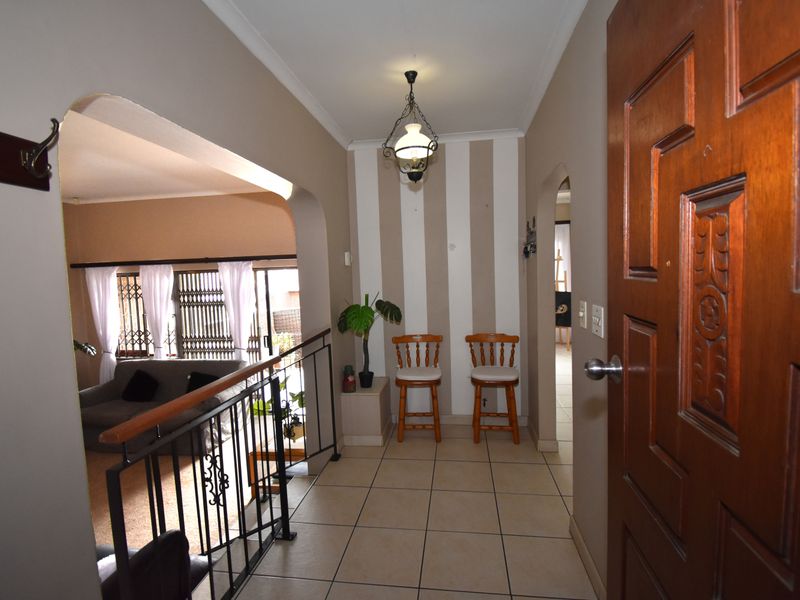 Entrance hall featuring tiled flooring, arched architectural details, and a wrought iron balustrade overlooking the living area.