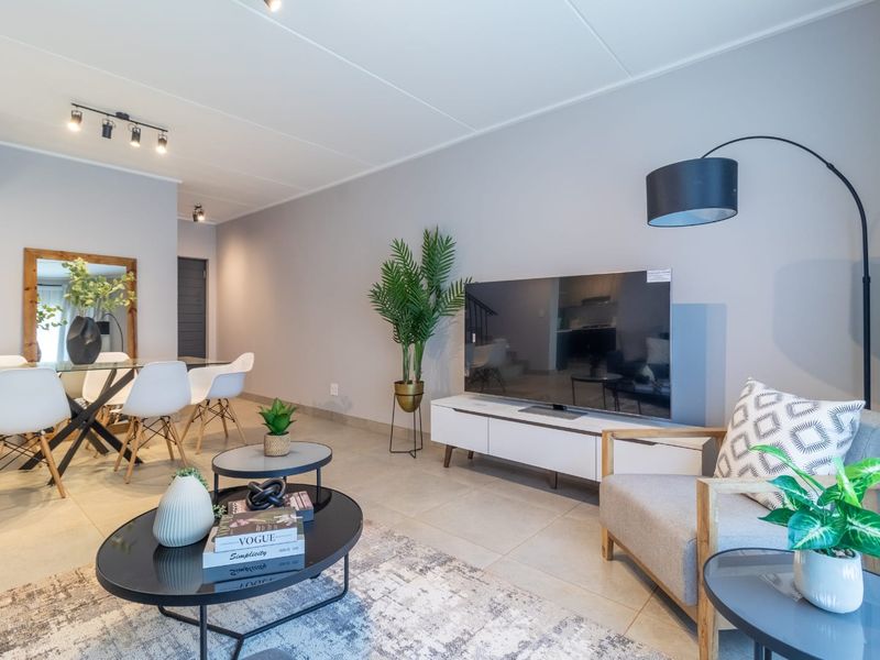 A bright and modern open-plan living and dining area featuring neutral tiled flooring and contemporary track lighting throughout the space.