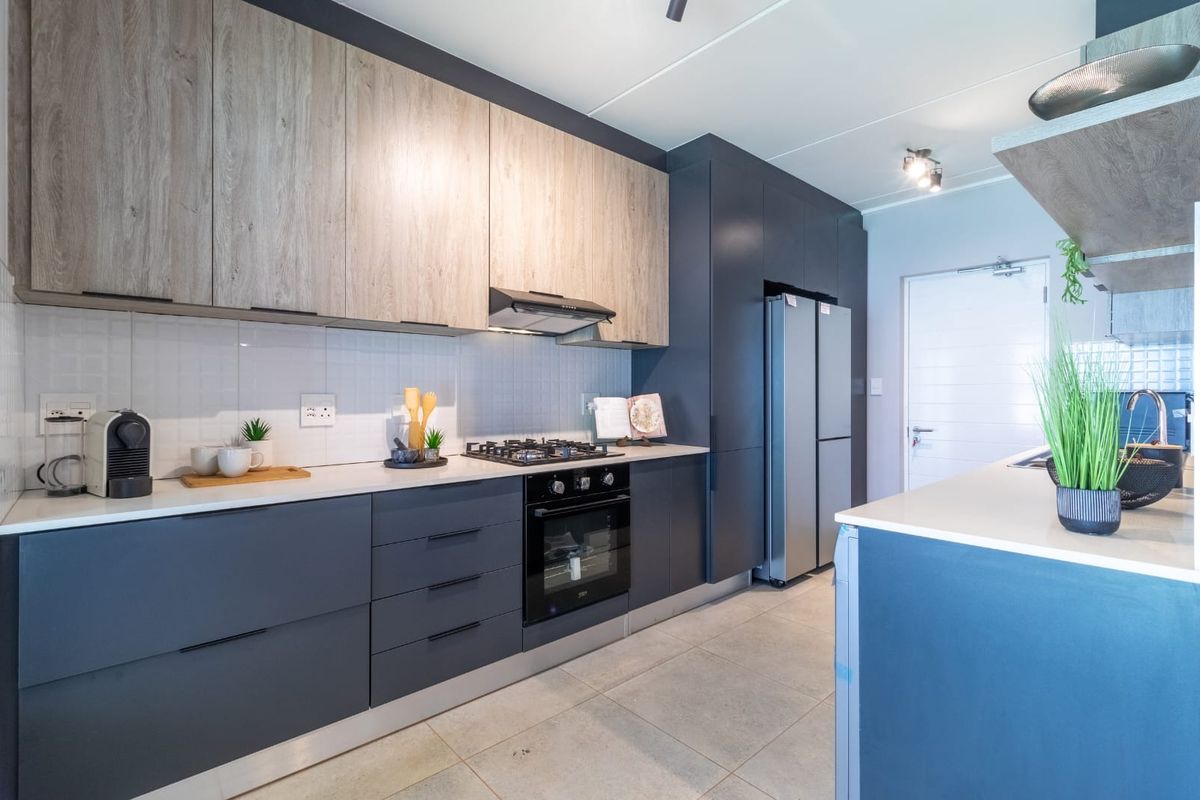 Modern kitchen featuring two-tone cabinetry, stone countertops, integrated gas hob, electric oven, and sleek tiled flooring in a contemporary townhouse setting.