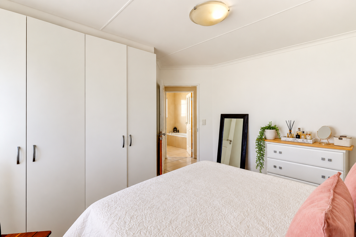 A well-maintained bedroom featuring ample built-in cupboard storage and direct access to an adjoining bathroom.