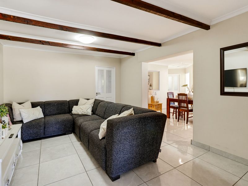 Open plan living and dining area featuring tiled flooring and exposed timber ceiling beams, creating a bright and connected living space.
