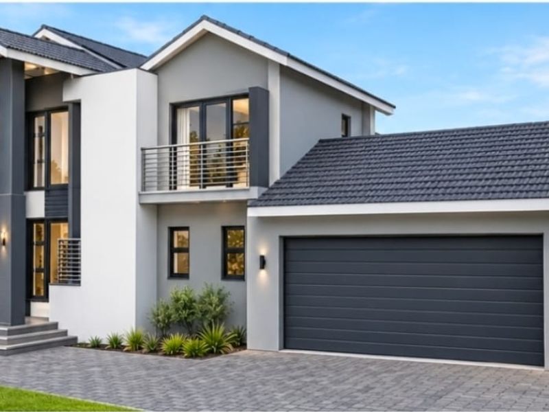 Modern double-story residential home featuring a contemporary facade, tiled roof, integrated double garage, and a private balcony with metal railings.