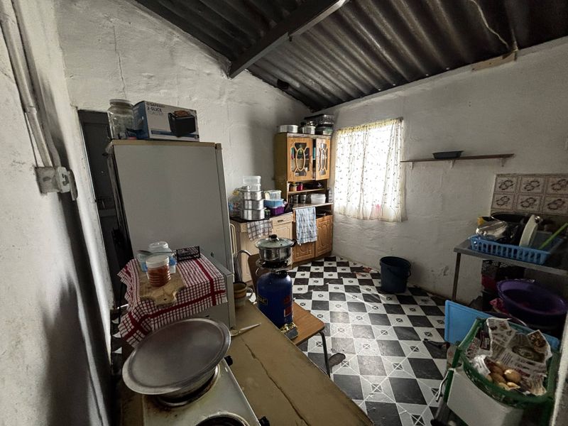 A rustic kitchen area featuring exposed rafters, tiled flooring, and basic wall finishes, offering significant potential for renovation and modernization.
