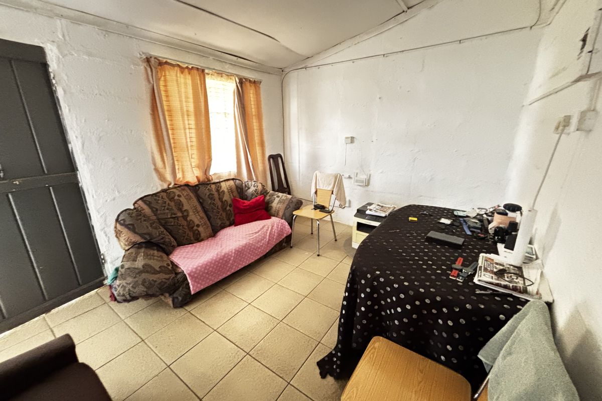 A living area featuring tiled flooring and a timber door, requiring significant cosmetic updates to the walls and ceiling to improve the overall condition.