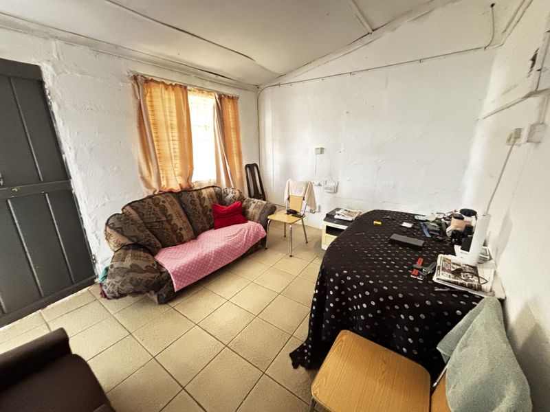 A living area featuring tiled flooring and a timber door, requiring significant cosmetic updates to the walls and ceiling to improve the overall condition.