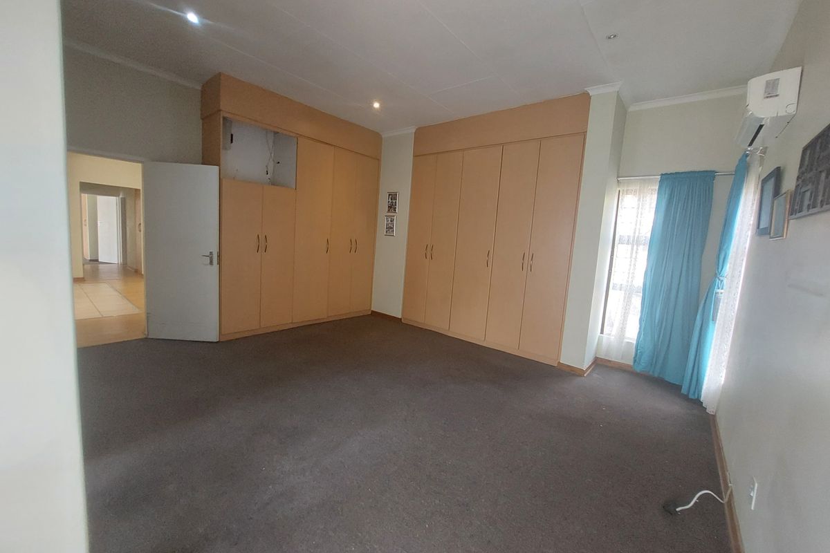 Spacious bedroom featuring extensive built-in cabinetry, carpeted flooring, and an integrated air conditioning unit, offering a blank canvas for personalization.