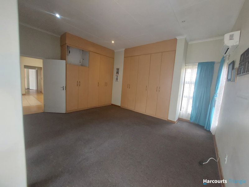 Spacious bedroom featuring extensive built-in cabinetry, carpeted flooring, and an integrated air conditioning unit, offering a blank canvas for personalization.