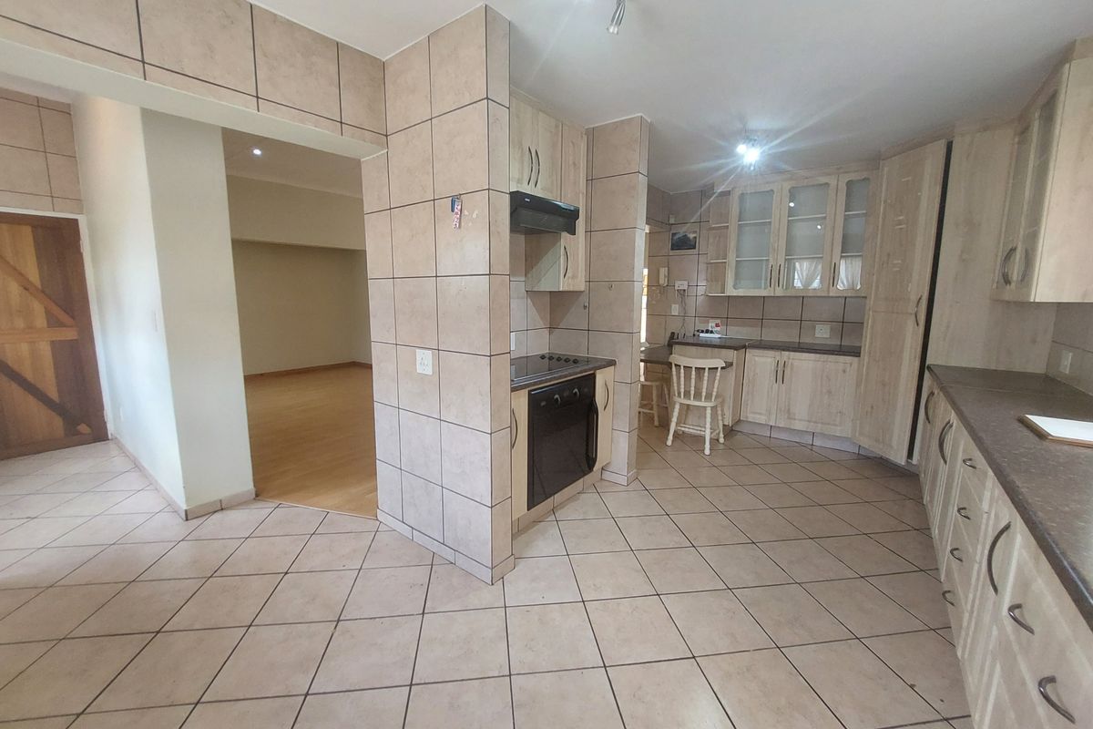 A functional kitchen featuring tiled flooring and walls, built-in cabinetry, and integrated cooking appliances, offering a practical layout with potential for modern updates.