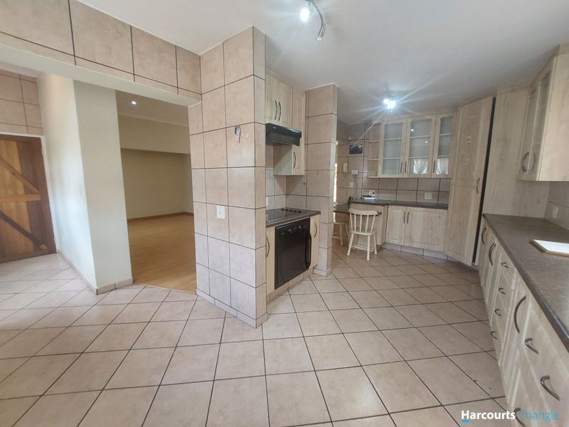 A functional kitchen featuring tiled flooring and walls, built-in cabinetry, and integrated cooking appliances, offering a practical layout with potential for modern updates.