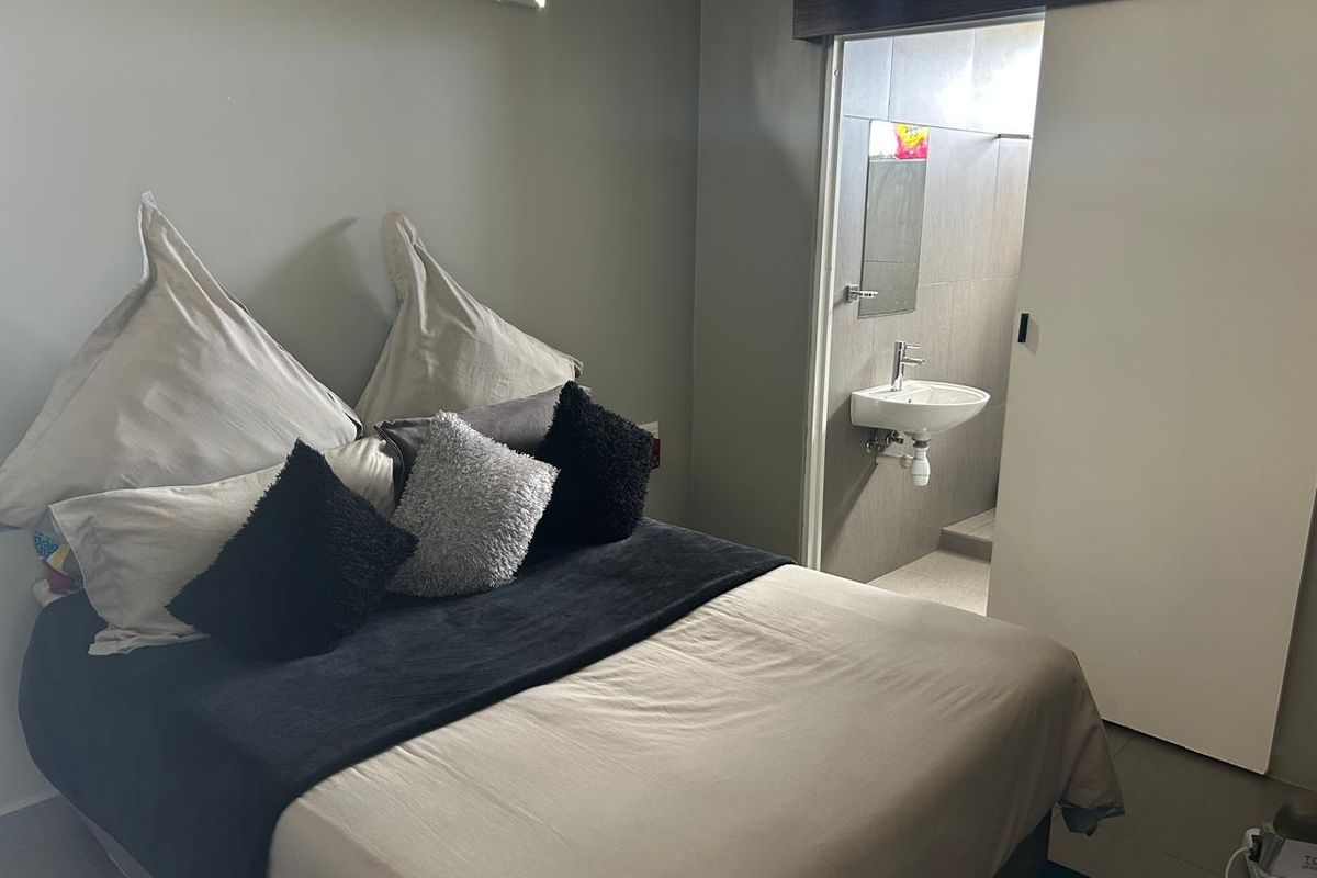 A bedroom featuring a sliding door leading to an en-suite bathroom with a wall-mounted basin and tiled finishes.