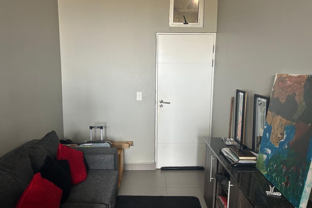 A living area featuring tiled flooring, a neutral wall finish, and a high-level transom window above an internal door.