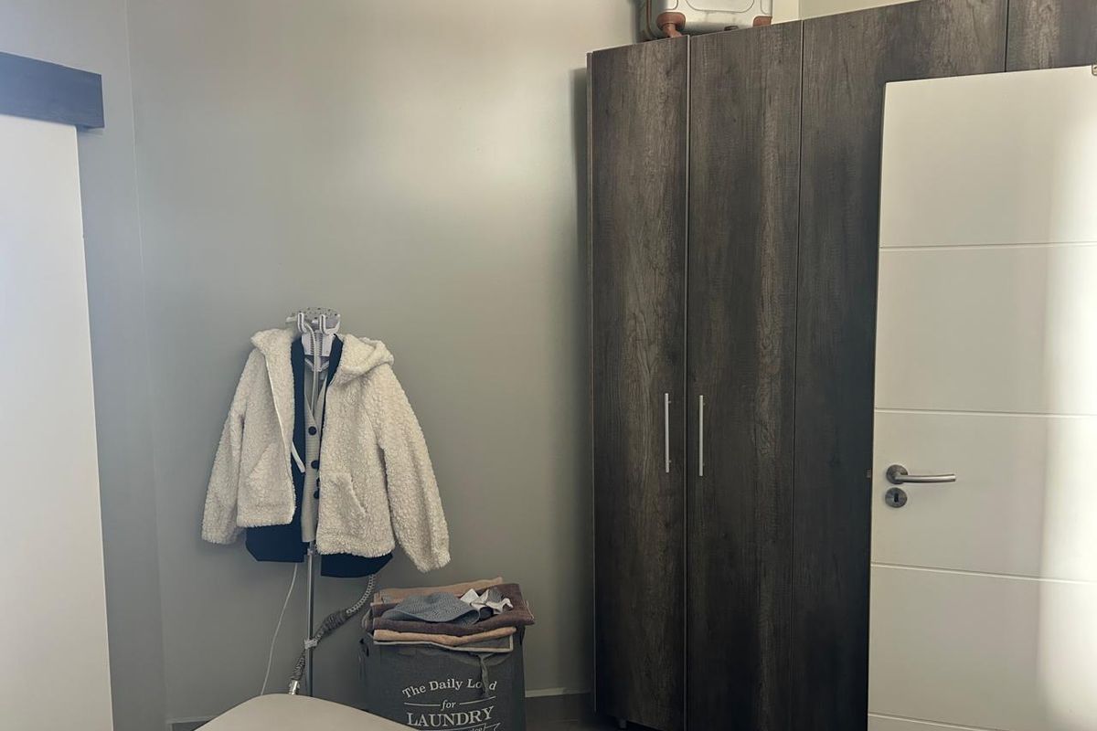 A bedroom featuring a dark wood-finish built-in wardrobe and a modern white internal door.