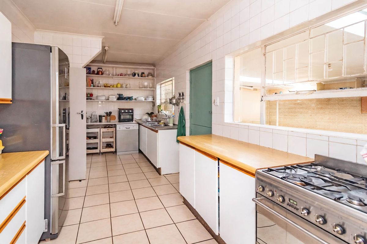 Functional kitchen featuring tiled walls and flooring, wooden countertops, gas stove, and ample built-in cabinetry with open shelving for storage.