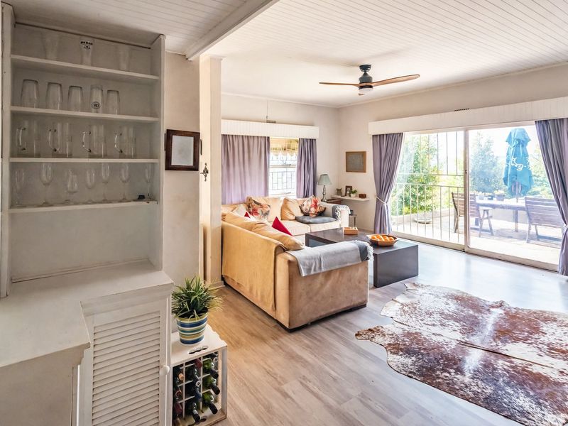 Bright living room featuring laminate flooring, a ceiling fan, and large sliding glass doors that open to an outdoor patio area.