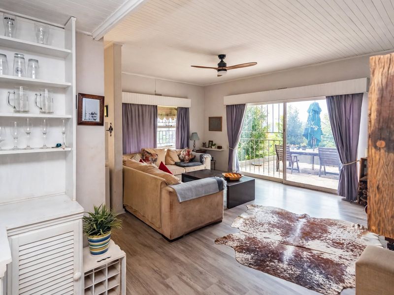 A bright living room featuring laminate flooring, a ceiling fan, and built-in shelving, with direct access to an outdoor patio through sliding glass doors.