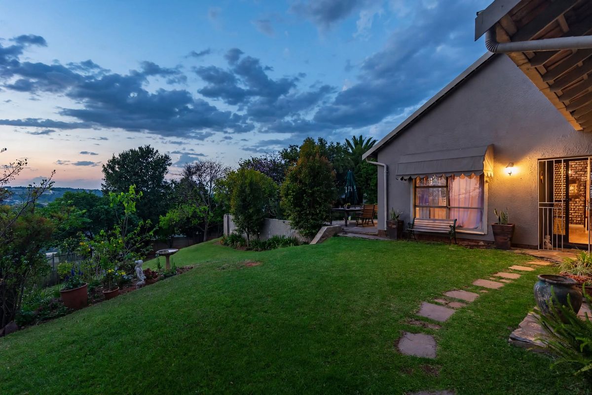 A well-maintained rear garden featuring a manicured lawn, stone pathway, and a paved patio area adjacent to the house exterior at dusk.