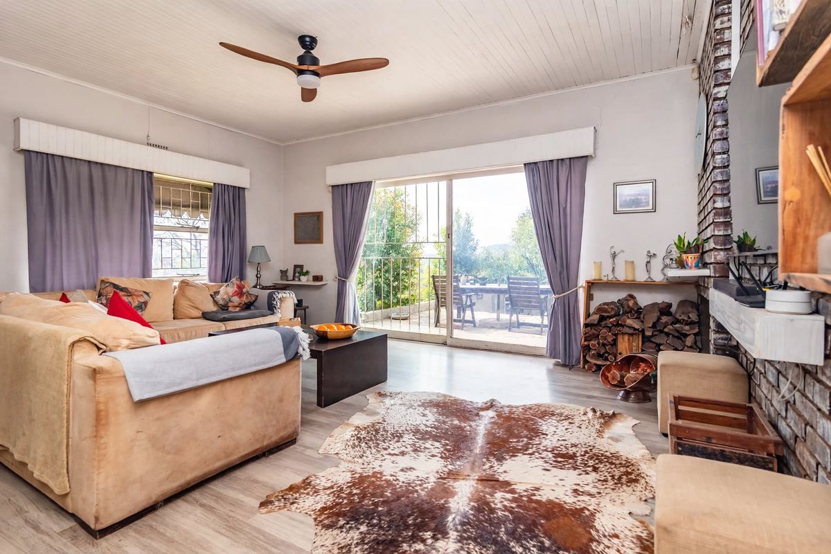 Spacious living room featuring a brick fireplace, timber panelled ceiling, ceiling fan, and sliding glass doors leading to an outdoor patio area.