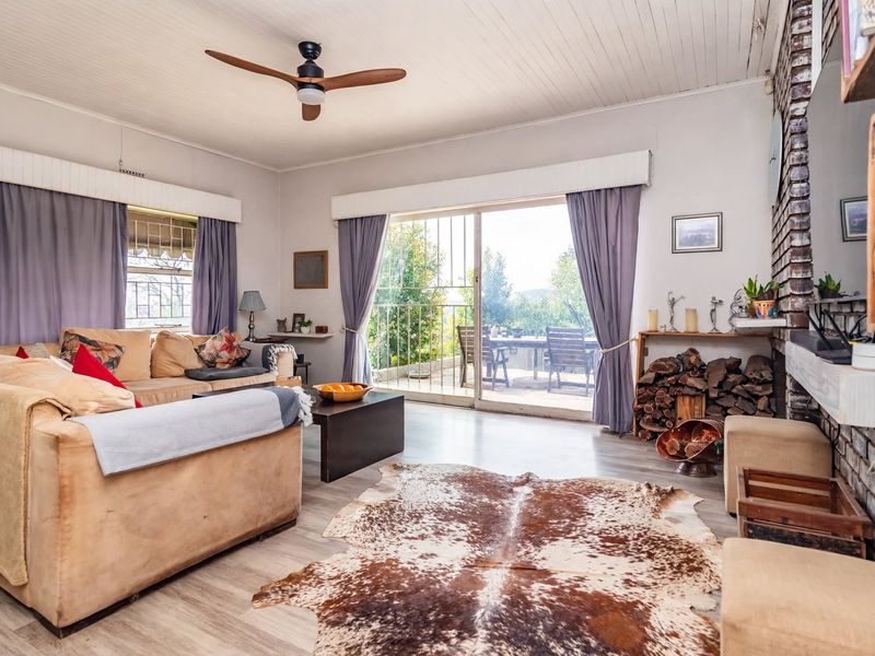 Spacious living room featuring a brick fireplace, timber panelled ceiling, ceiling fan, and sliding glass doors leading to an outdoor patio area.