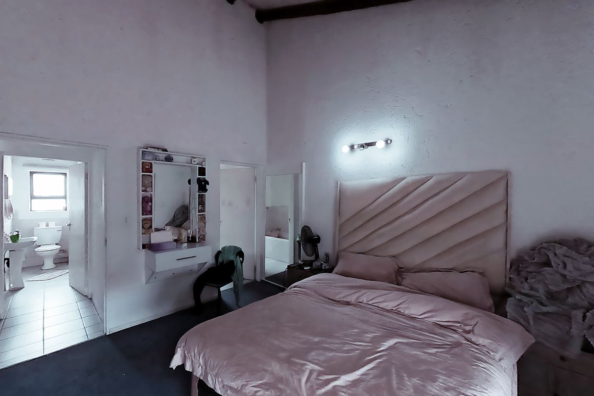 Spacious bedroom featuring a vaulted ceiling, wall-mounted vanity, and direct access to an en-suite bathroom.