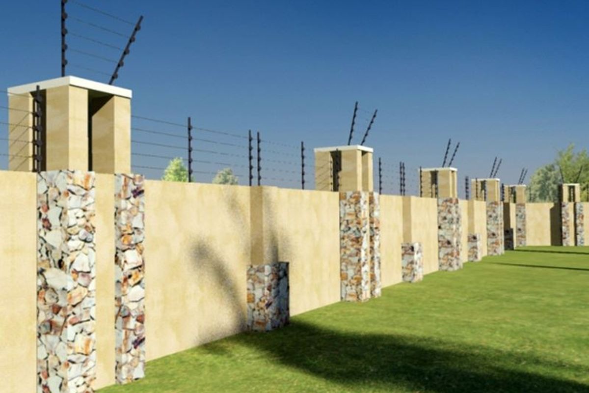 A secure perimeter wall featuring stone-clad masonry pillars and integrated electric fencing, bordering a well-maintained lawn area.