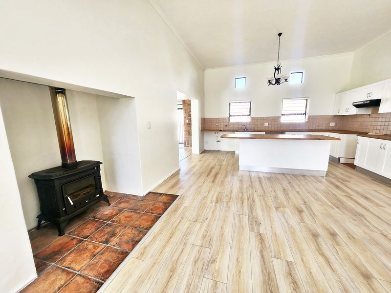 Spacious open-plan living and kitchen area featuring a freestanding fireplace, laminate flooring, and a central kitchen island with built-in cabinetry.