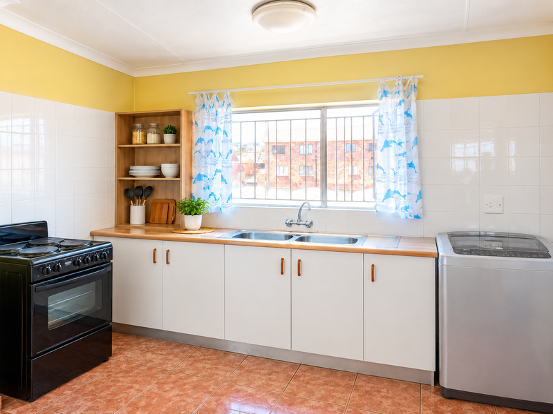 A functional kitchen featuring white cabinetry, a double sink, tiled backsplash, and ceramic flooring, with a window providing natural light and security bars.