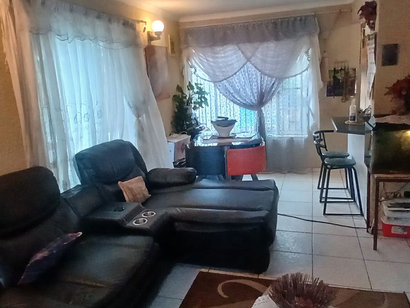An open-plan living and dining area featuring tiled flooring and a breakfast bar, offering a functional layout for daily living.