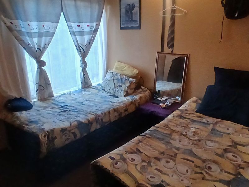 A compact bedroom featuring a window with curtains, suitable for a single or twin setup.