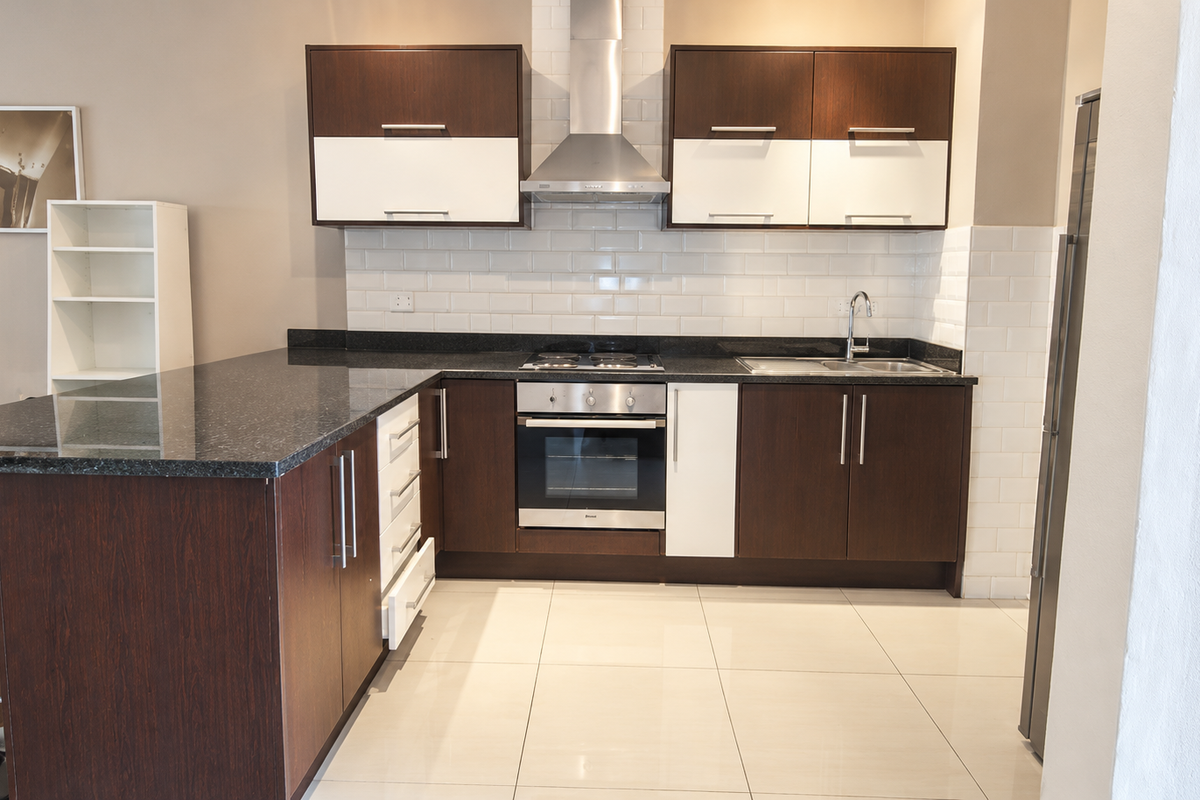 Modern kitchen featuring dark wood and white cabinetry, granite countertops, subway tile backsplash, and integrated stainless steel appliances.