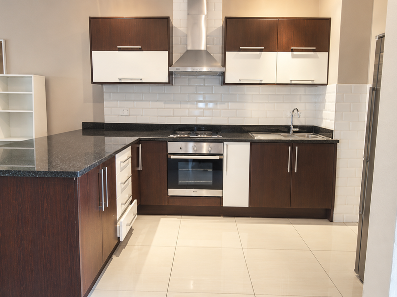 Modern kitchen featuring dark wood and white cabinetry, granite countertops, subway tile backsplash, and integrated stainless steel appliances.