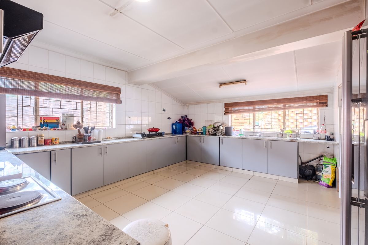 Spacious kitchen featuring extensive built-in cabinetry, laminate countertops, tiled flooring, and a functional layout with ample workspace and natural light.