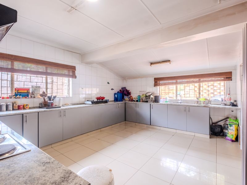 Spacious kitchen featuring extensive built-in cabinetry, laminate countertops, tiled flooring, and a functional layout with ample workspace and natural light.