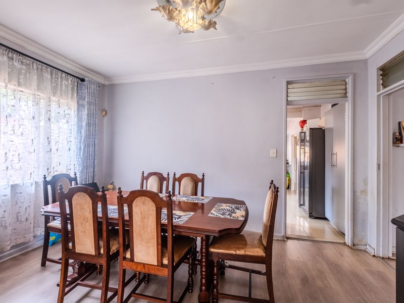 Dining room featuring laminate flooring and coving, with a doorway leading to the kitchen area.