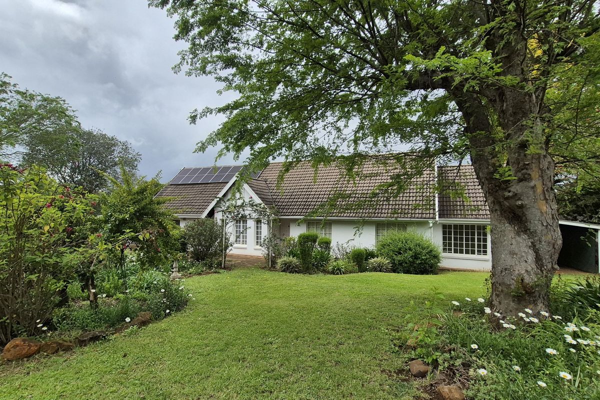 A well-maintained single-story home featuring a tiled roof, solar panels, and a spacious, established garden with mature trees.