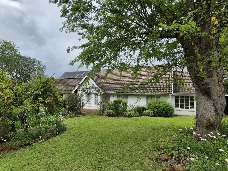 A well-maintained single-story home featuring a tiled roof, solar panels, and a spacious, established garden with mature trees.