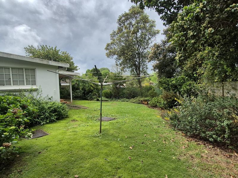 A private rear garden featuring a well-maintained lawn, established greenery, and a boundary wall, providing a quiet outdoor space.