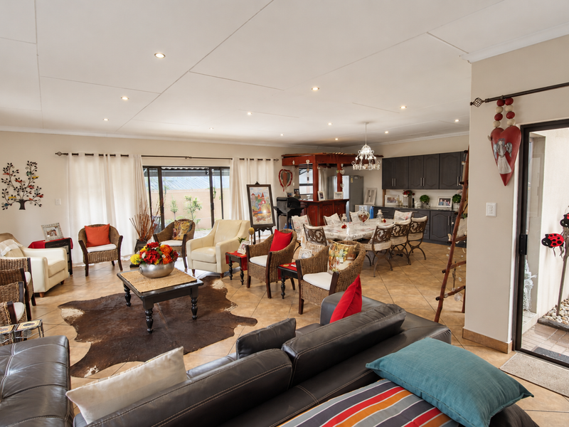 Spacious open-plan living and dining area featuring tiled floors, recessed lighting, and a functional kitchen with dark cabinetry and a built-in bar.
