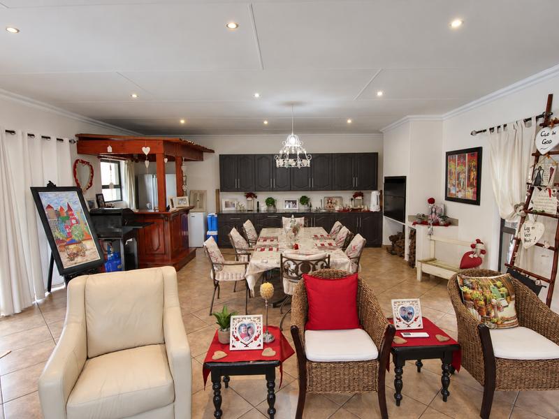 Spacious open-plan living and dining area featuring tiled floors, built-in cabinetry, a wooden bar counter, and a built-in fireplace.